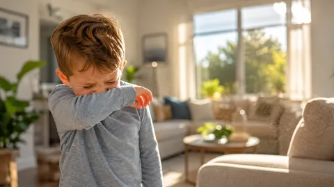 Young child sneezing into their elbow in a sunlit Florida living room with airborne dust and allergens visible in the light